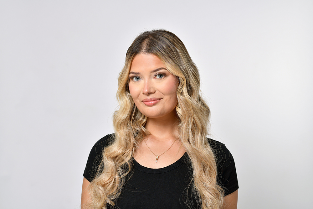 Modèle femme blonde aux yeux bleus avec haut noir. Séance photo en studio pour salon de coiffure spécialisé dans les extensions de cheveux. Photo prise par Alexandre Escudero Photographe Grenoble.